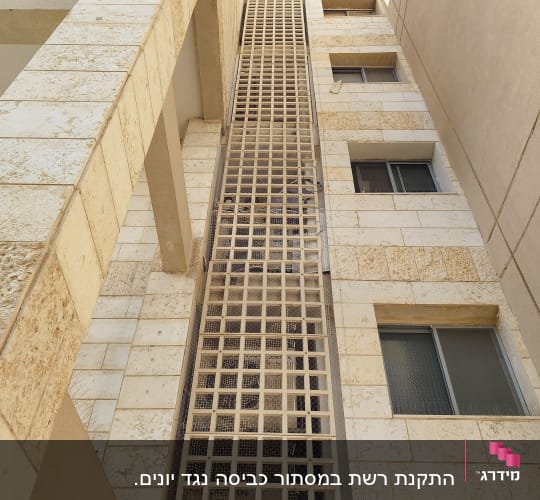 רשת מתכת על קיר בניין למניעת כניסת יונים